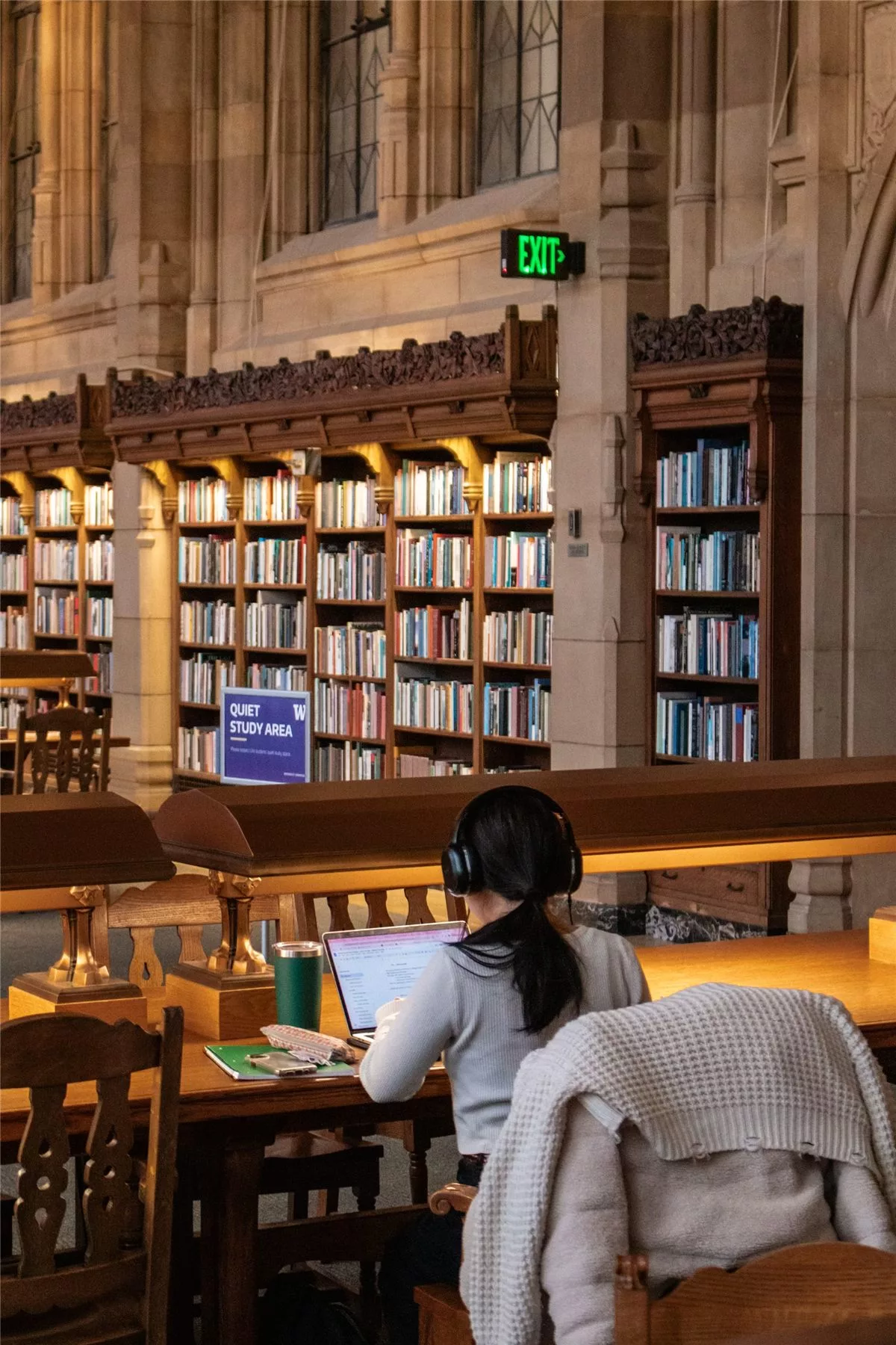 Une étudiante travaille à une table dans une bibliothèque universitaire historique