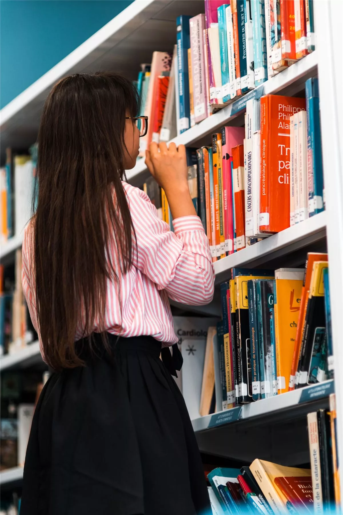 Une usagère parcourt les rayons d’une bibliothèque publique