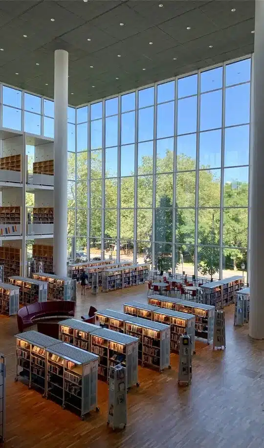 Bright two-story library with rows of shelves and a tall glass wall