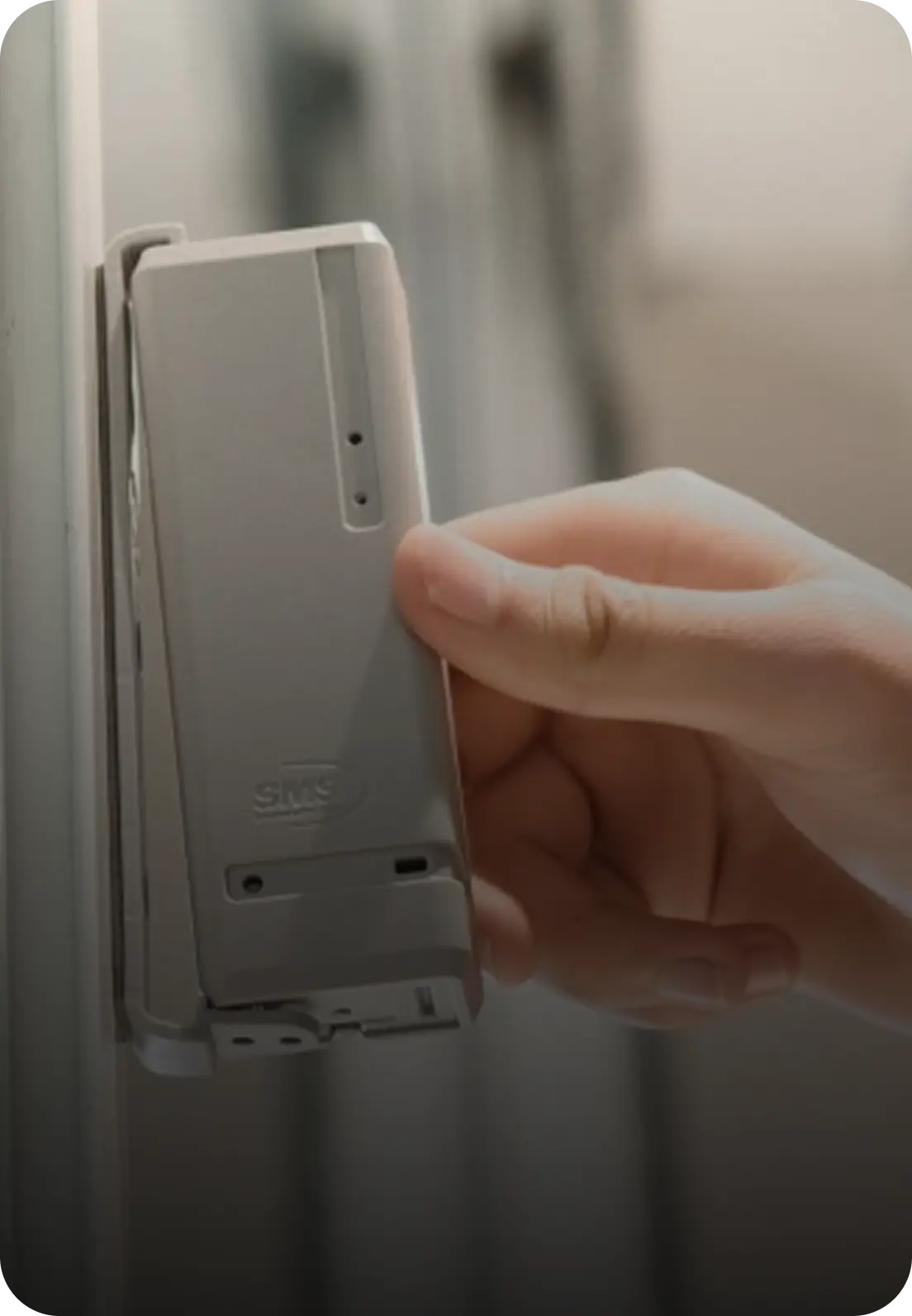 A hand pressing a PEARL bracket onto a white door frame