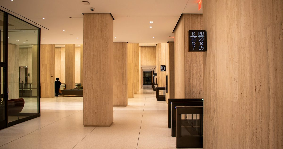Office building lobby with entry turnstiles and an elevator bank sign